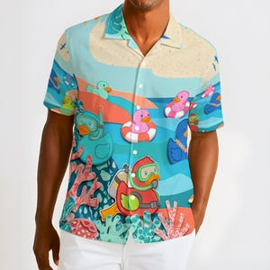 May include: Short-sleeved button-down shirt with a vibrant, cartoonish beach scene. The design features colorful ducks with scuba gear and inner tubes, set against a backdrop of ocean waves, coral, and a sandy beach. The shirt has a classic collar and a relaxed fit.