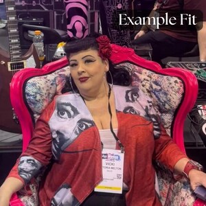 Puede incluir: Una chaqueta roja con un dise&ntilde;o de retrato en las mangas y la parte delantera. La chaqueta se usa sobre una camiseta blanca. El fondo incluye una silla rosa y una guitarra. Una etiqueta con el nombre dice "Vicki Victoria Melton".