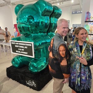 May include: A large, metallic emerald green sculpture of a gummy bear standing on a black base. A white rectangular sign attached to the bear reads: DEPT. OF CORRECTIONS, NEW YORK, NY, 6-6-07, BEAR, GUMMY. The artist signature is written in white on the base.