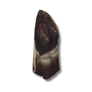 May include: A blazer featuring a dark, multi-colored printed pattern that resembles a classical oil painting. The garment has a notched lapel, long sleeves, and a structured silhouette, captured from a side profile view against a plain background.