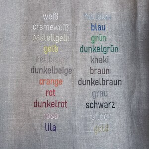 May include: A fabric swatch with a variety of color names embroidered in different colors, including white, cream, yellow, orange, red, pink, purple, blue, green, brown, gray, black, silver, and gold.