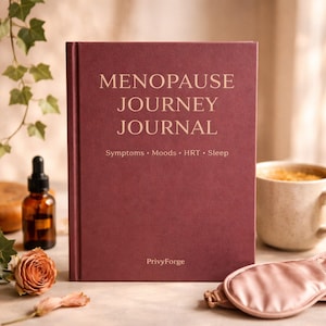 May include: A maroon journal titled "MENOPAUSE JOURNEY JOURNAL" with gold lettering. The journal includes the words "Symptoms • Moods • HRT • Sleep" and the brand name "PrivyForge". A cup of coffee, a sleep mask, a bottle of oil, and a rose are also in the image.
