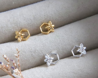 May include: A pair of gold and silver bee and honeycomb stud earrings. The earrings are small and delicate, and they would make a great gift for someone who loves bees.
