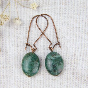 May include: A pair of copper wire earrings with green agate oval stones.