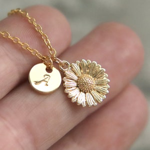 Puede incluir: Collar de oro con un peque&ntilde;o dije de margarita y un dije redondo con la letra A grabada.