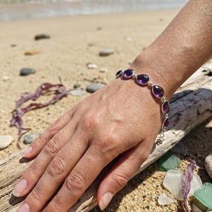 Pulseira leve em prata 925 com pedra natural de ametista roxa lapidada em rosa, formato irregular e acabamento em bisel. Ideal para casamentos, aniversários e outras ocasiões especiais.