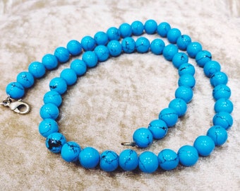 Les boules turquoise forment un collier de perles synthétiques.