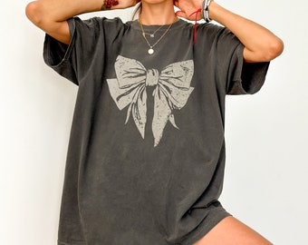 May include: A charcoal gray oversized t-shirt with a large white bow graphic printed on the front.