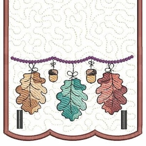 Puede incluir: Un panel de tela blanco con un borde festoneado marrón. El panel presenta una guirnalda marrón, morada y verde de hojas de roble y bellotas. La guirnalda cuelga de un anillo marrón en la parte superior del panel.