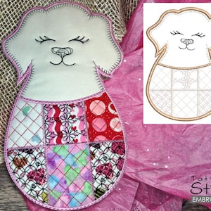 Puede incluir: Una aplicación de perro de fieltro blanco con un contorno cosido rosa y un diseño de patchwork. El perro tiene ojos negros y una nariz negra. El diseño de patchwork incluye telas rosas, rojas y blancas.