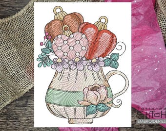 May include: Embroidered design of a vintage style teacup filled with hearts and flowers. The teacup is decorated with a green and pink striped pattern and a single pink flower.