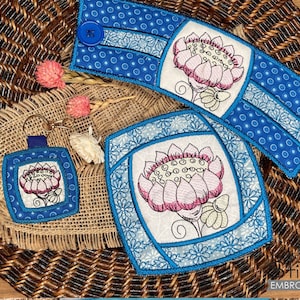 Puede incluir: Tres posavasos de tela bordados en azul y blanco con un diseño floral. Los posavasos tienen forma cuadrada, rectangular y redonda. Los posavasos están sobre una superficie de mimbre marrón.