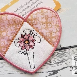 May include: A pink heart-shaped fabric patch with a white cross and a pink flower embroidered on it. The text "Seek His will and He will show you which path to take" is visible on the patch.