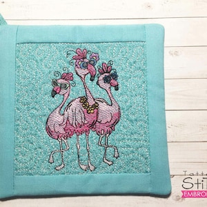 Könnte beinhalten: Ein türkisfarbener Topflappen mit weißem Hintergrund, der ein gesticktes Design aus drei pinkfarbenen Flamingos mit Sonnenbrillen zeigt. Die Flamingos stehen auf einem türkisfarbenen Hintergrund mit weißem Rand.