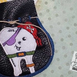 Pode incluir: Bolsa de fada dos dentes em couro preto com um design de dente pirata. O dente tem um tapa-olho roxo, uma bandana vermelha e um cinto verde. A bolsa tem uma borda azul e um fecho de cordão. Logotipo Tattered Stitch Embroideries.