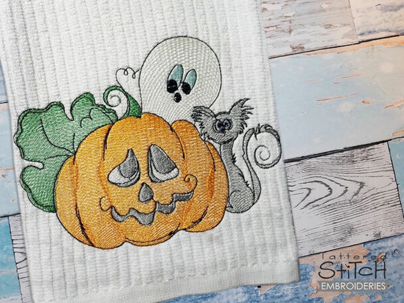 May include: Embroidered design of a pumpkin with a ghost and a cat. The pumpkin has a green stem and a friendly face. The ghost is white with black eyes and a small mouth. The cat is gray with a long tail and a black nose.