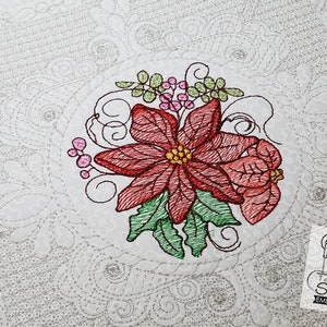 May include: Embroidered design of a red poinsettia with green leaves and pink berries. The design is surrounded by a decorative border of swirls and dots.