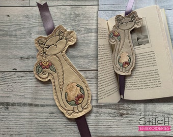 May include: A beige felt bookmark with an embroidered design of a cat holding a flower. The bookmark is attached to a brown ribbon.