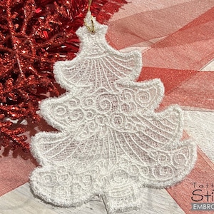 May include: White lace Christmas tree ornament with a delicate, intricate design. The ornament is hanging from a red and white ribbon.