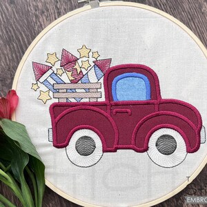 Peut inclure: Camionnette rouge avec une benne pleine de feux d'artifice. Le camion a un pare-brise bleu et des roues blanches. Les feux d'artifice sont rouge, blanc et bleu.