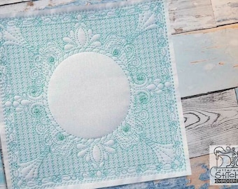 May include: A white square embroidery hoop with a teal blue floral design and a circular opening in the center. The design is intricate and detailed, with a delicate floral pattern.