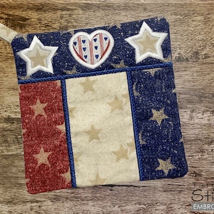 May include: A red, white, and blue patriotic pot holder with a heart and stars design. The pot holder is made of fabric and has a loop for hanging.