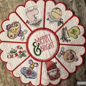 May include: White fabric Christmas ornament with red trim and a scalloped edge. The ornament features a variety of embroidered designs, including a candy cane, a snowman, and ornaments. The center of the ornament features the text "Merry & Bright".