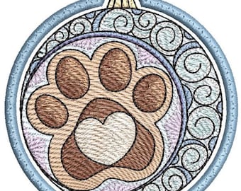 May include: A blue and white Christmas ornament with a brown paw print and a white heart in the center. The ornament has a swirl design around the edge.