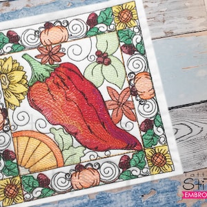 Op de afbeelding: Borduurontwerp met een rode peper, herfstbladeren, pompoenen en zonnebloemen in een vierkant frame. Het ontwerp is perfect voor een borduurproject met een herfstthema.