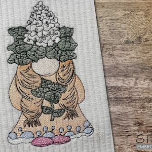May include: Embroidered design of a gnome with a large bouquet of white flowers on a gray background.