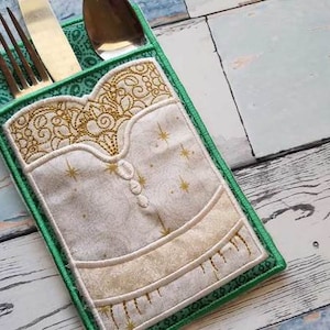 Pode incluir: Um porta-talheres de tecido verde e branco com um design bordado em dourado. O porta-talheres tem um bolso para guardar talheres.