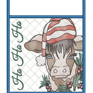 May include: A white quilted fabric with a blue border and a red and white striped Santa hat on a brown and white cow with green holly and red berries. The text "Ho Ho Ho" is written in green on the fabric.