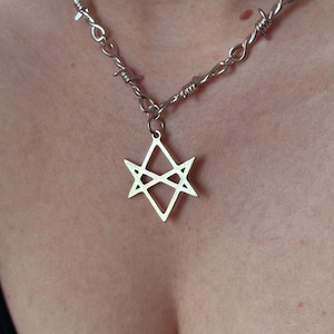 May include: A silver necklace with a barbed wire chain and a star-shaped pendant.