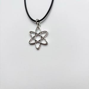 以下が含まれることがあります： 六芒星のデザインが特徴の、シルバーカラーのペンダントネックレス。ペンダントは黒いコードで吊り下げられています。ネックレスは白い背景に表示されています。