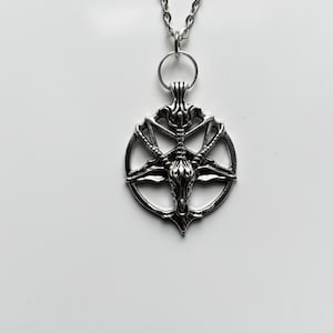 May include: Silver pendant necklace with a pentagram design and a goat head at the centre. The necklace has a chain and a circular bail. The words "Pissy Prints" are written in cursive at the bottom.