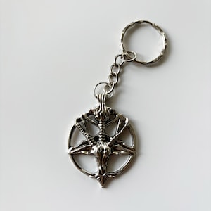 May include: Silver keychain featuring a pentagram with a goat's head in the centre.