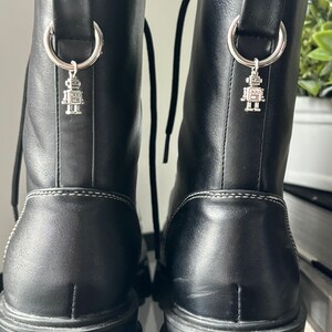 May include: Black leather boots with a chunky platform sole and a silver robot charm attached to the back of each boot.