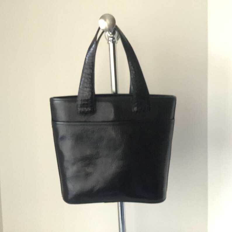 May include: A black leather tote bag with a top handle and a structured shape.