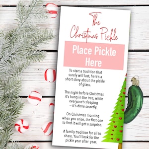 May include: A Christmas Pickle card with text and a green glass pickle ornament. The card reads "The Christmas Pickle" and "Place Pickle Here". Peppermint candies and a frosted evergreen branch are also in the image.