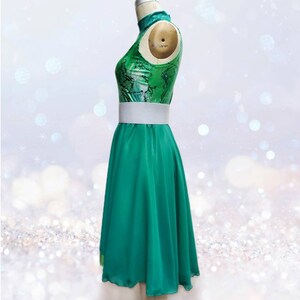Puede incluir: Un vestido de baile verde y blanco con cuello alto y cintur&oacute;n blanco. La falda es una falda de c&iacute;rculo completo.