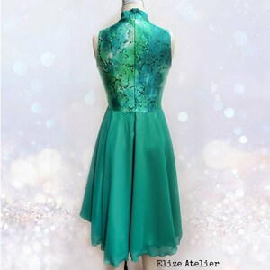 Puede incluir: Un vestido verde sin mangas con cuello alto y un corpi&ntilde;o estampado. La falda es de tejido de gasa fluido.
