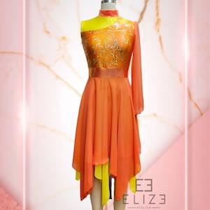 Puede incluir: Un vestido asimétrico sin mangas con cuello alto y manga larga. El corpiño es de tela estampada en dorado y amarillo con un cinturón de cinta dorada. La falda es de gasa naranja y amarilla en capas.