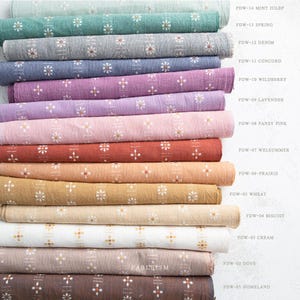 May include: A stack of fabric rolls in various colors, including green, gray, blue, purple, pink, orange, yellow, and cream. Each roll is printed with a white floral pattern. The fabric names are listed on the right side.