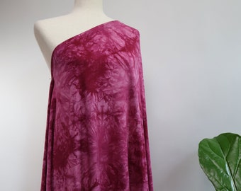 May include: A pink tie-dye fabric with a white background. The fabric is draped over a white mannequin.