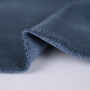 May include: Close-up of a soft, blue fabric with a textured surface. The fabric is folded over, showing the underside.
