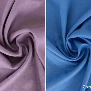 May include: Two fabric swatches, one lilac and one cornflower blue, are displayed. The lilac fabric is on the left, with the word "Lilac" at the bottom. The cornflower blue fabric is on the right, with the word "Cornflower" at the bottom.