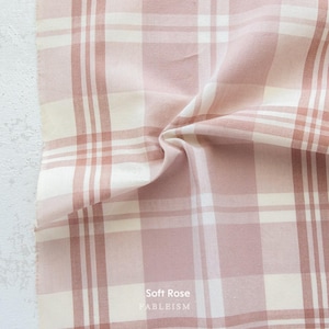 a close-up view of a fabric with a pink and white plaid pattern, folded and crumpled.