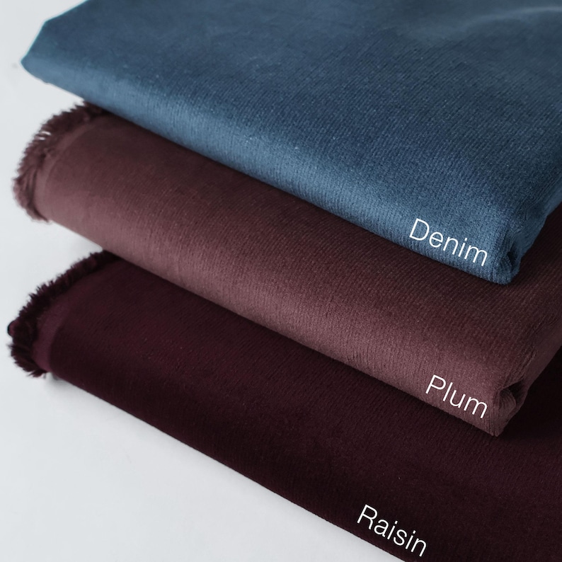 May include: Three fabric swatches in different shades of purple and blue. The top swatch is a dark blue denim, the middle swatch is a deep purple plum, and the bottom swatch is a dark burgundy raisin.