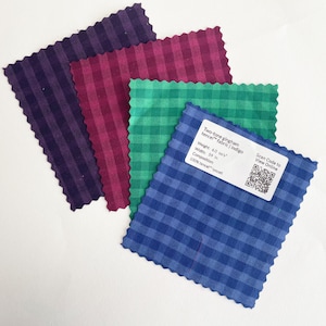 May include: Four fabric swatches in different colors: indigo blue, green, burgundy, and purple. The swatches are made of a gingham pattern and are labeled "Two-tone gingham tencel fabric | Indigo". The label also includes the weight, width, composition, and a QR code to view online.