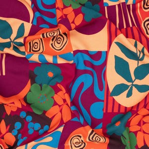 May include: A colourful fabric with a patchwork design. The textile features floral and abstract shapes in orange, teal, purple, and cream. The bold pattern creates a striking visual effect.